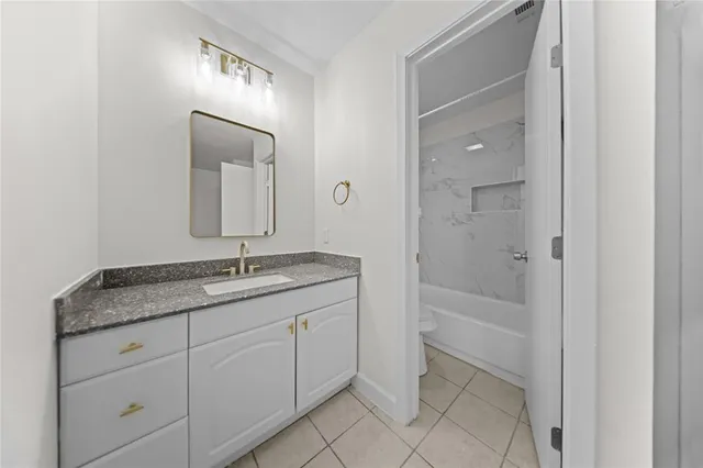 a bathroom with a granite countertop sink two mirror and a bathtub