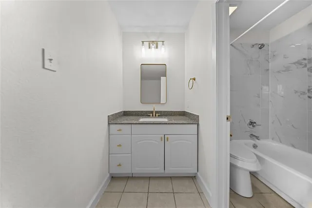 a bathroom with a granite countertop sink a toilet and shower