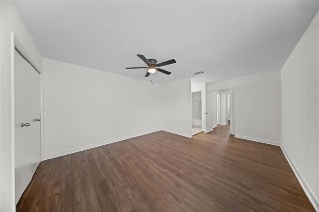 a view of empty room with wooden floor and ceiling fan