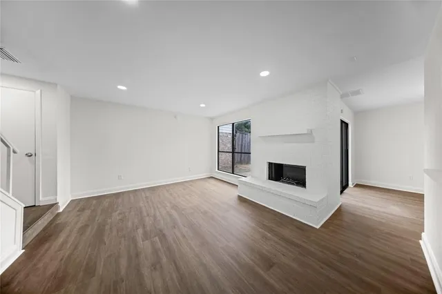 an empty room with wooden floor and fireplace