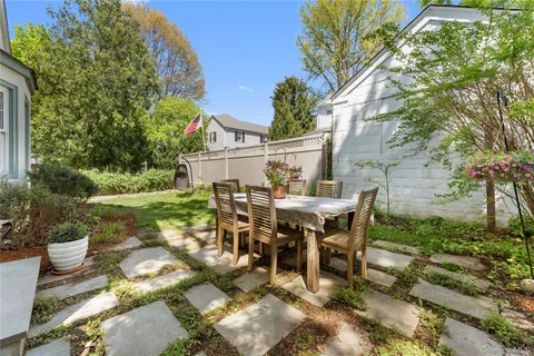 a view of a patio with table and chairs potted plants and large tree
