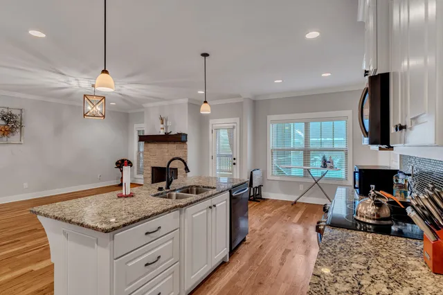 a kitchen with granite countertop a stove a sink a refrigerator and a fireplace
