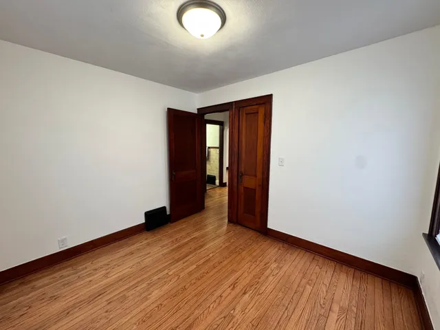 an empty room with wooden floor and natural light