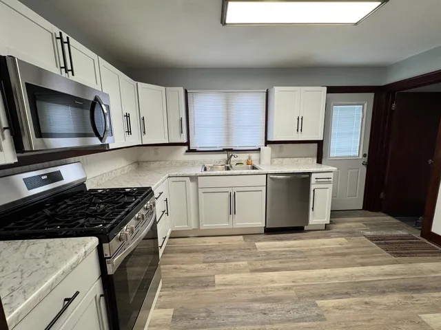 a kitchen with stainless steel appliances a stove a microwave a sink and cabinets