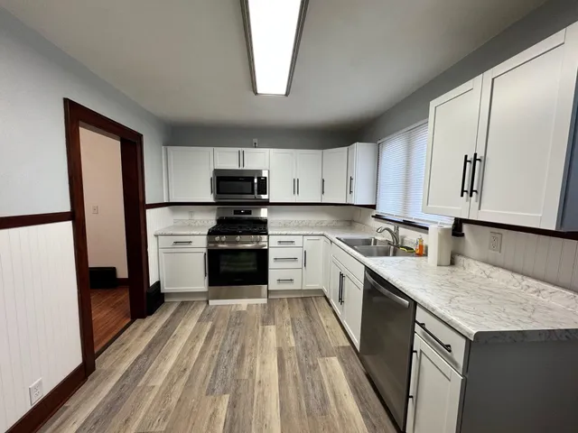 a kitchen with white cabinets stainless steel appliances and sink