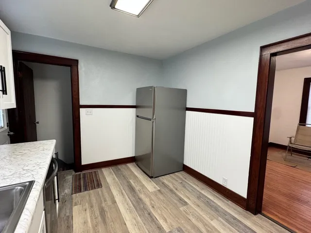 a view of kitchen with refrigerator and wooden floor