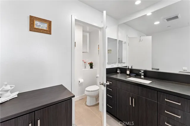 a bathroom with a granite countertop sink a toilet a large mirror and shower