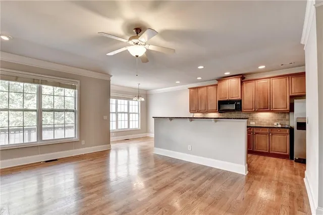 a view of an empty room wooden floor and a kitchen