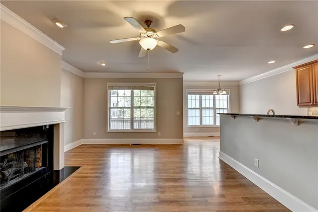 a view of a hallway with wooden floor and a kitchen
