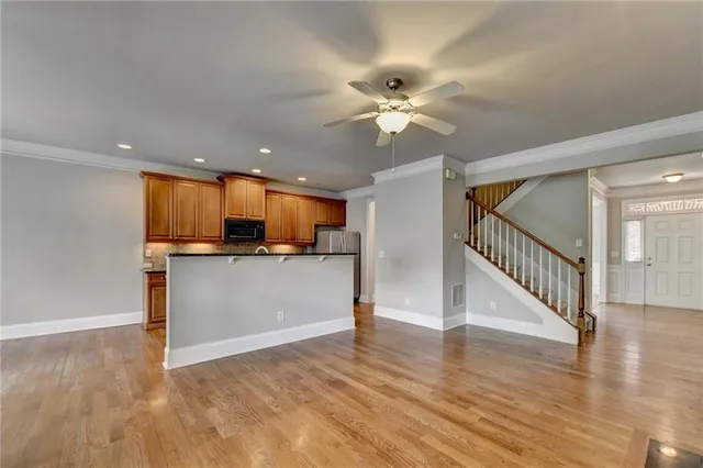 a large kitchen with stainless steel appliances granite countertop a stove top oven a sink dishwasher and white cabinets with wooden floor