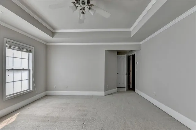 an empty room with a chandelier fan and windows