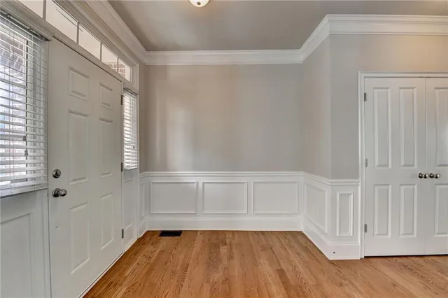 an empty room with wooden floor chandelier fan and windows