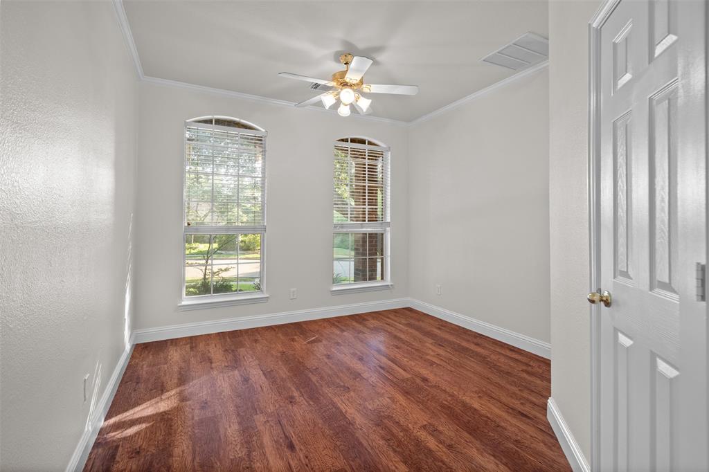 4405 Ridgecove Drive Rowlett, TX 75088 - Photo 18 of 37 Wood-finish flooring, two arched windows with blinds, ceiling fan with light fixture, white paneled door, and crown molding