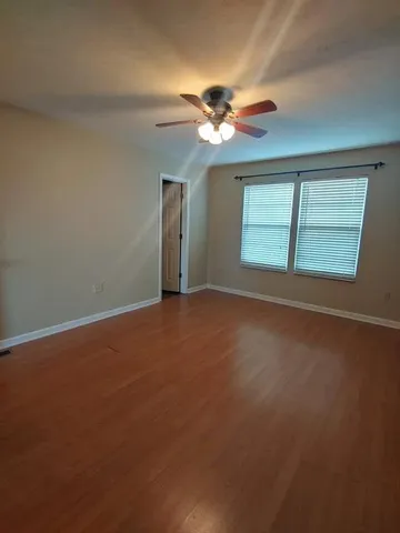 a view of an empty room with chandelier fan and a window