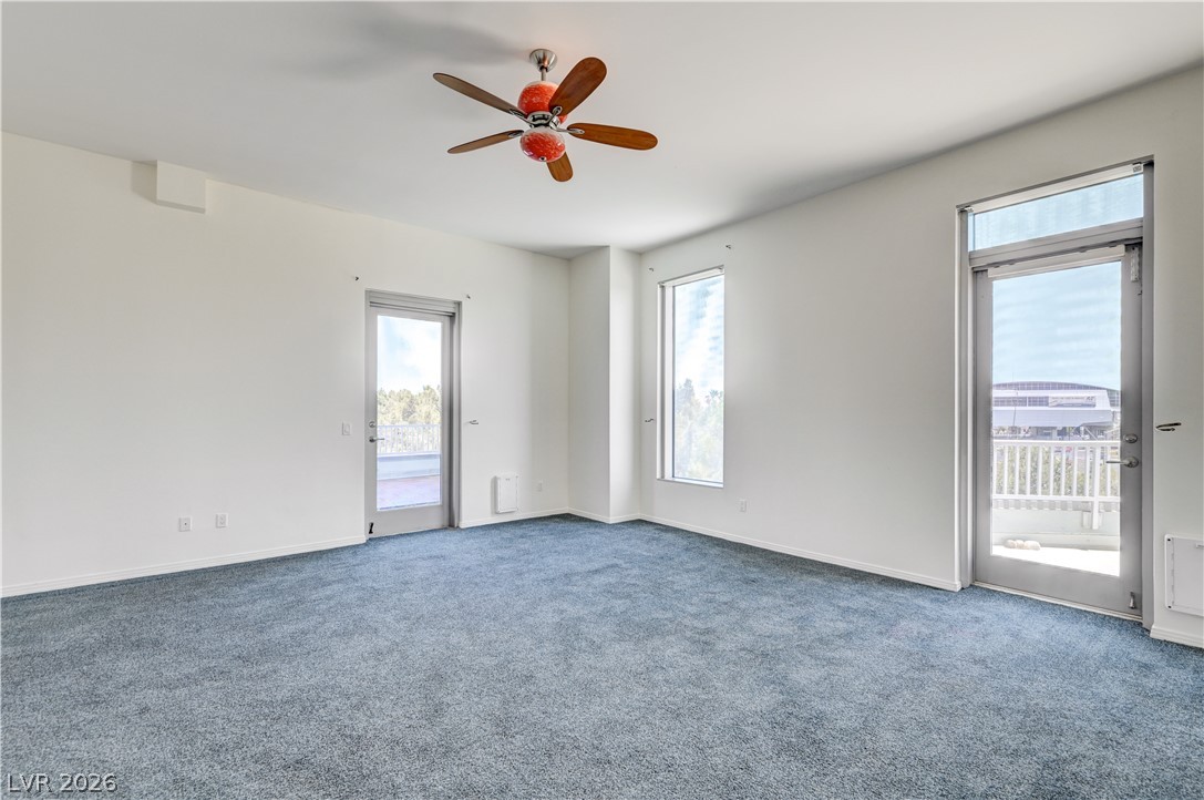 360 East Desert Inn Road, Unit 402 Las Vegas, NV 89109 - Photo 16 of 40 A spacious room featuring a ceiling fan and generous natural illumination from large windows and a glass door.