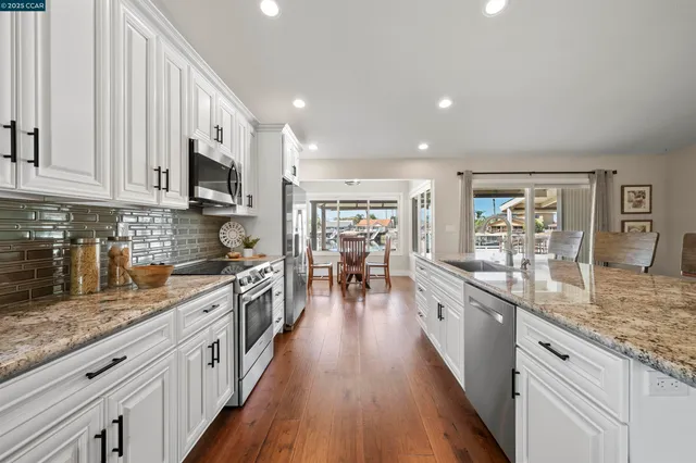 a kitchen with stainless steel appliances granite countertop a stove top oven a sink and a refrigerator