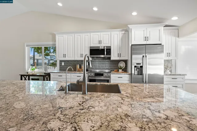 a large kitchen with stainless steel appliances granite countertop a lot of counter space and wooden floors