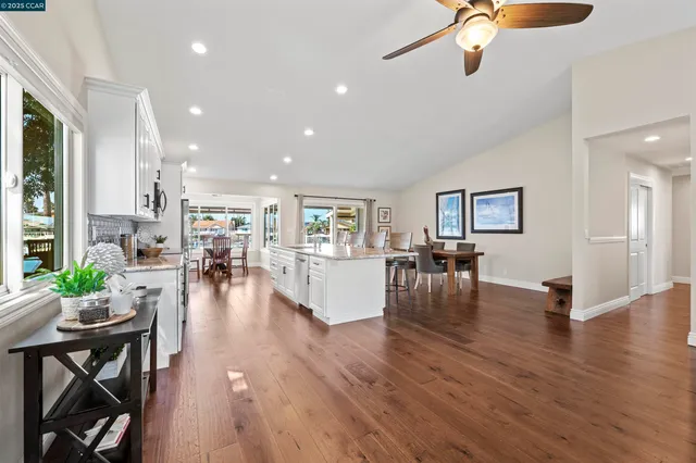 a kitchen with a table chairs wooden floors and white stainless steel appliances