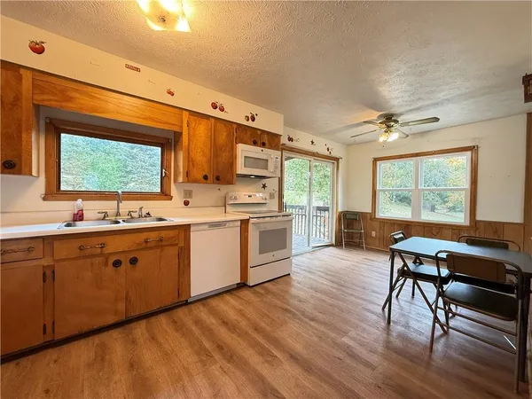 a large kitchen with kitchen island a large window a sink appliances and cabinets