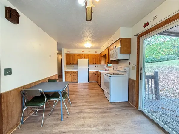 a kitchen with stainless steel appliances kitchen island granite countertop dining table chairs and a large window