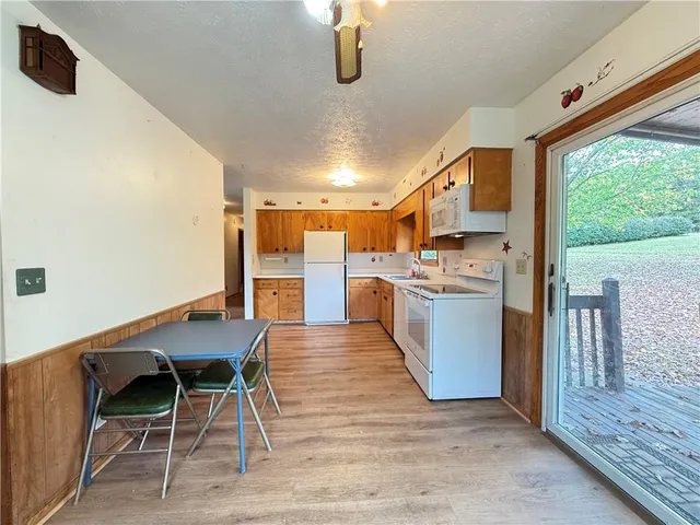 a kitchen with stainless steel appliances kitchen island granite countertop dining table chairs and a large window