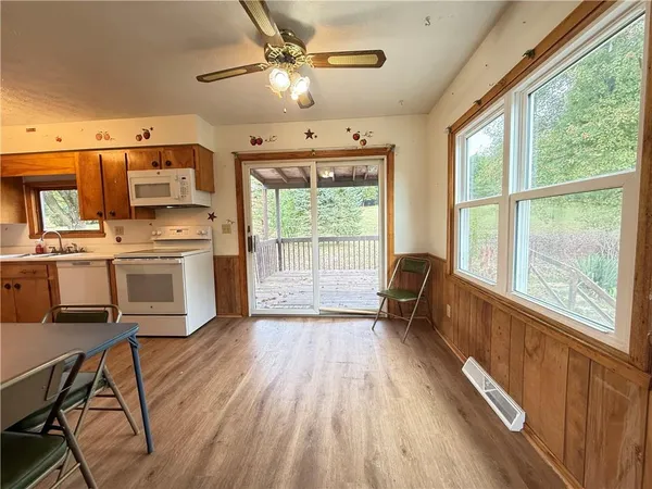 a view of a kitchen with furniture a ceiling fan and wooden floor