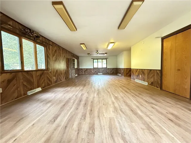 a view of empty room with wooden floor and fan