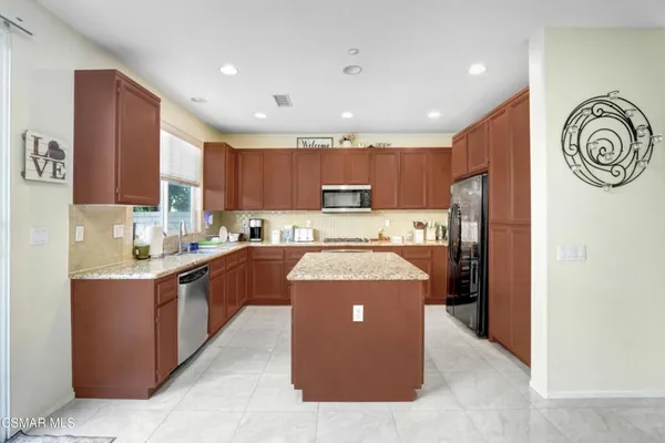 a kitchen with kitchen island stainless steel appliances cabinets a sink and a counter top space