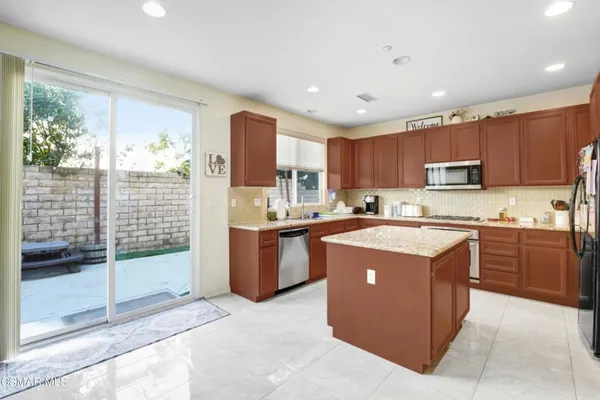 a kitchen with kitchen island wooden cabinets a stove a sink and a refrigerator