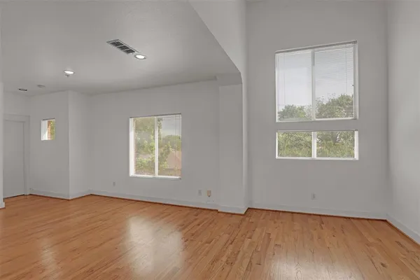 an empty room with wooden floor and windows