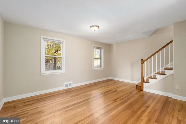 a view of an empty room with wooden floor and stairs