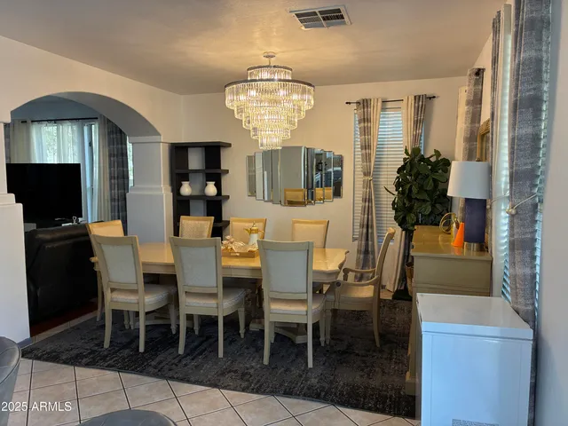 a kitchen with stainless steel appliances granite countertop a refrigerator a sink a stove a dining table and chairs