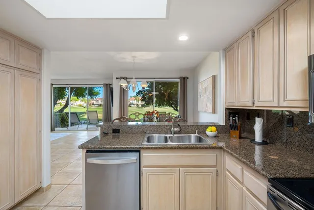 a kitchen with stainless steel appliances granite countertop a sink a stove and a wooden cabinets