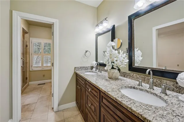 a bathroom with a granite countertop double vanity sink and a mirror