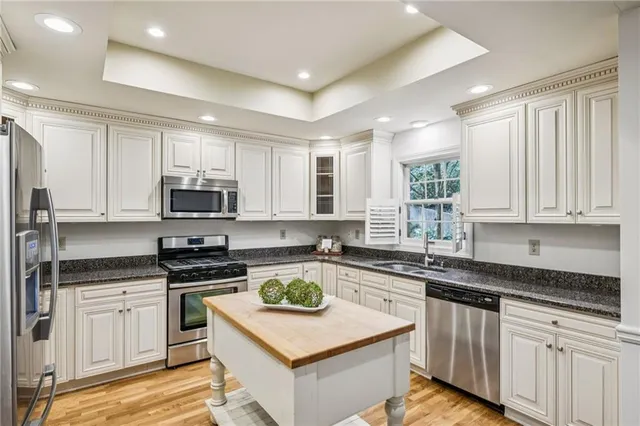 a kitchen with stainless steel appliances white cabinets a sink a stove a refrigerator and microwave