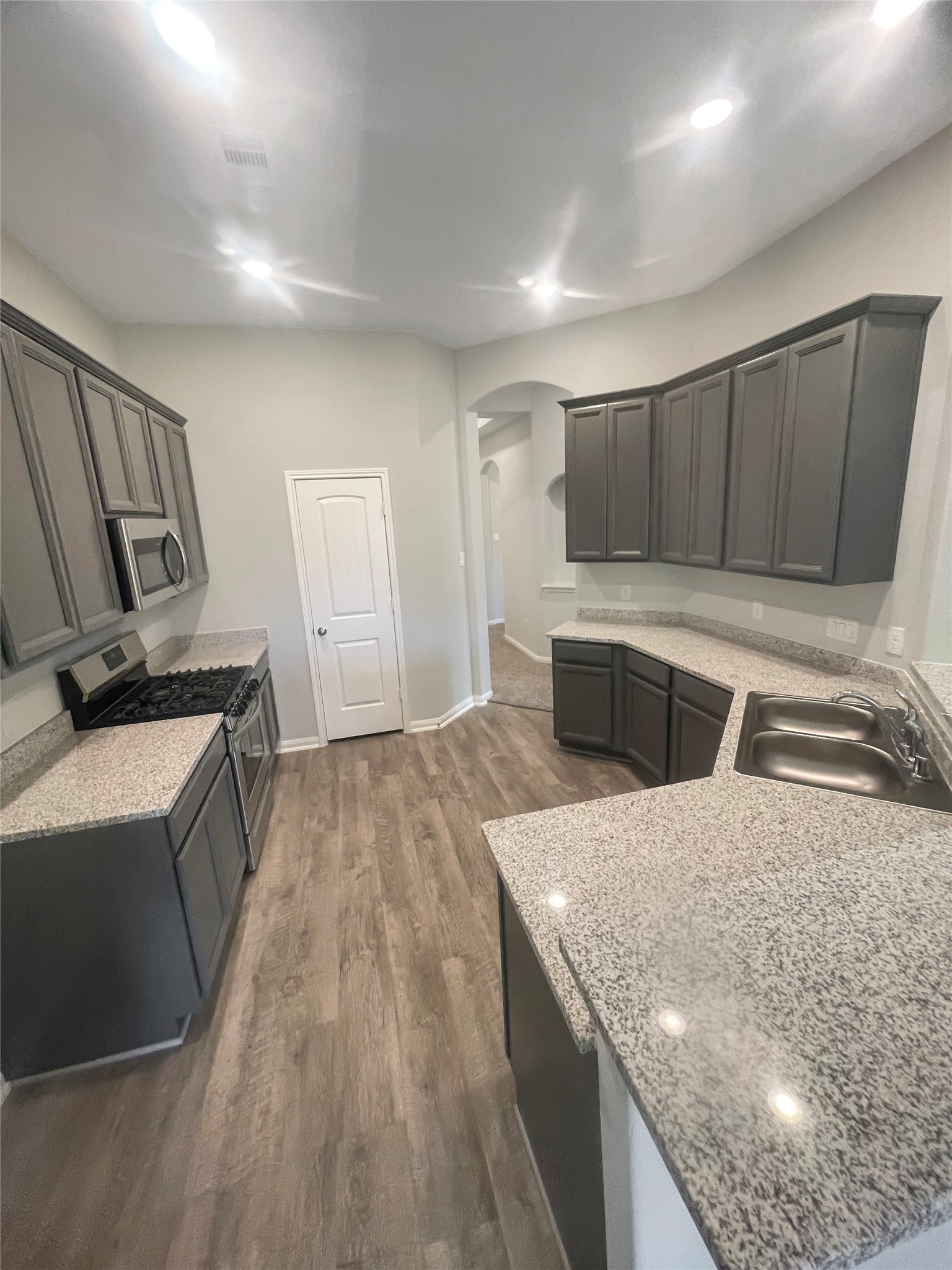25421 Honus Wagner Way Splendora, TX 77372 - Photo 6 of 24 a kitchen with granite countertop a sink a stove and a wooden floors