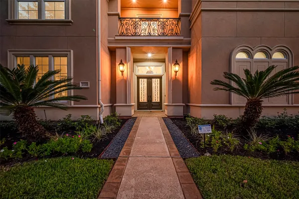 a view of a brick house with many windows and a flower garden