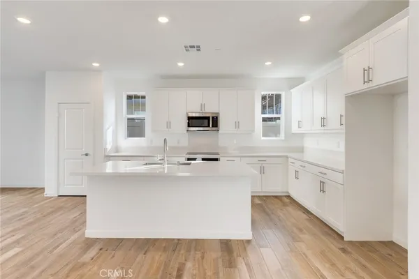a large kitchen with cabinets wooden floor and stainless steel appliances