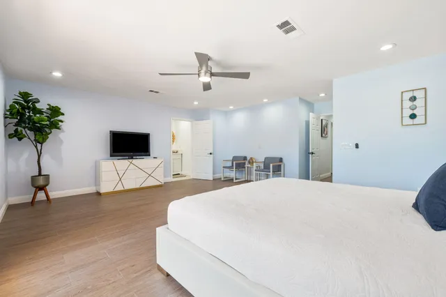 a spacious bedroom with a bed and a flat screen tv