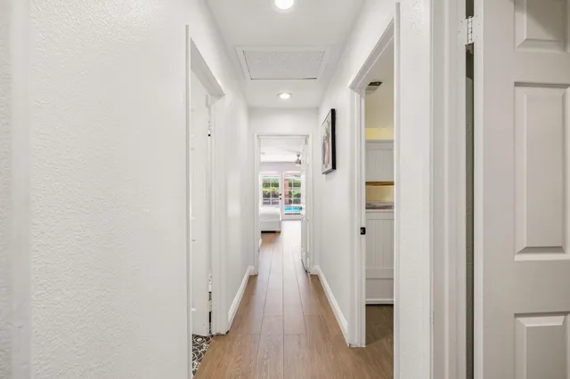 a view of a hallway with wooden floor and a bathroom