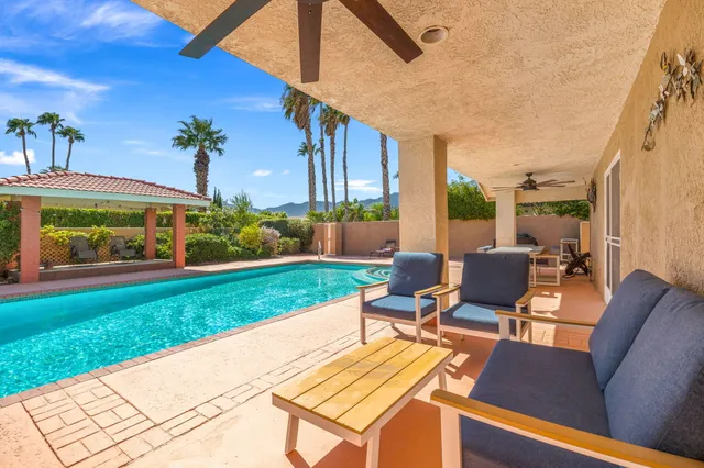 a view of a patio with couches table and chairs with wooden fence and plants