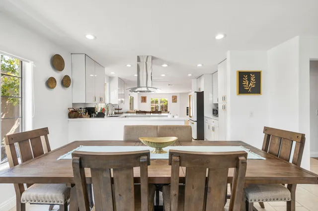 a kitchen with stainless steel appliances kitchen island granite countertop a table chairs and a refrigerator