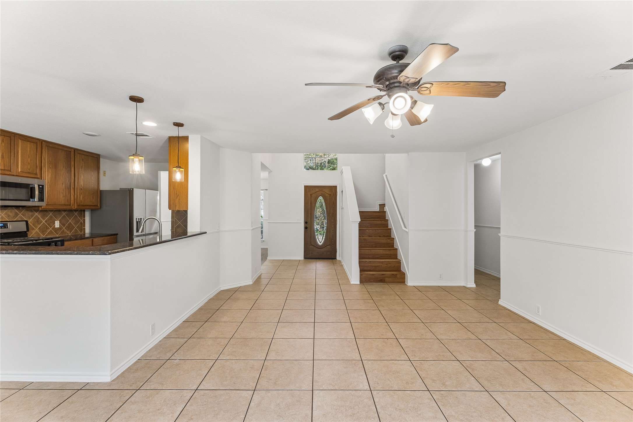 2372 Paradise Ridge Drive Round Rock, TX 78665 - Photo 13 of 40 A tiled living area seamlessly transitions to a well-appointed kitchen and an inviting entryway with a wooden staircase.