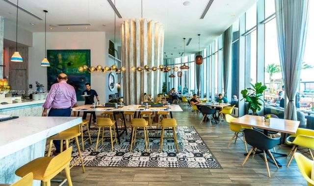 a view of a dining room with furniture one side kitchen view and wooden floor