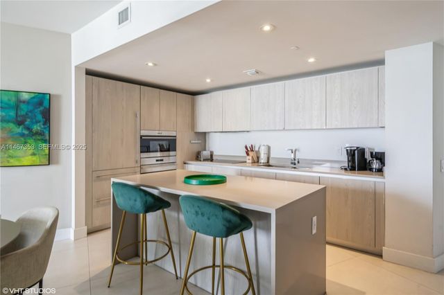 a kitchen with stainless steel appliances granite countertop a table chairs sink and cabinets