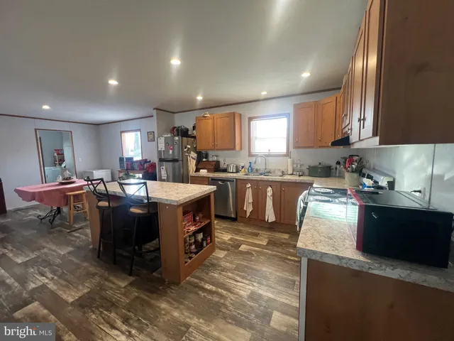 a kitchen with stainless steel appliances kitchen island granite countertop a stove a sink a refrigerator and a microwave