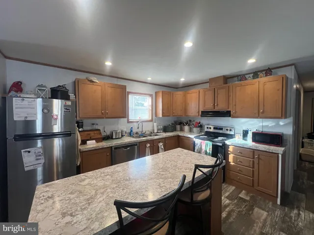 a kitchen with refrigerator a stove a sink a dining table and chairs