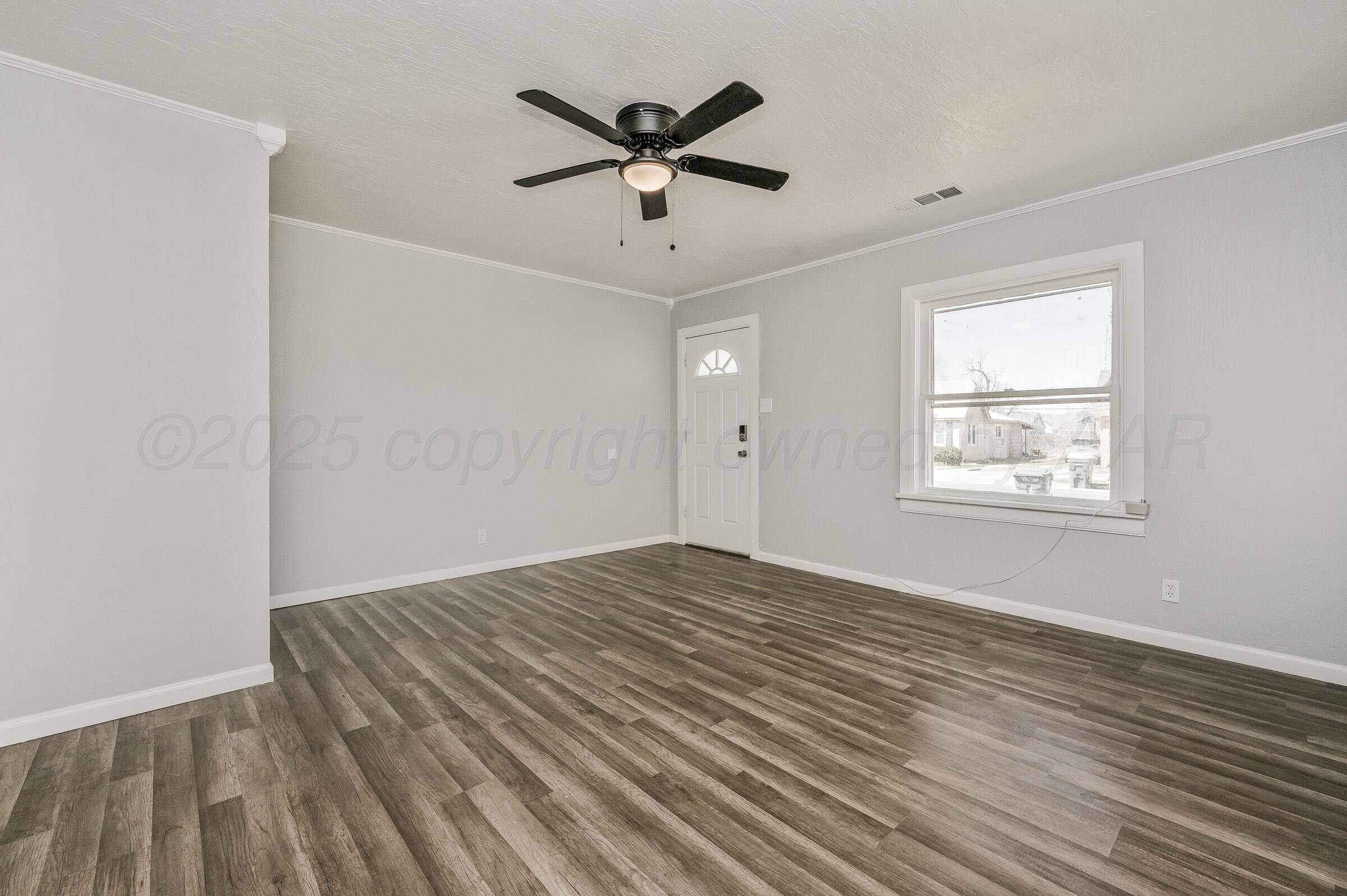 3705 South Polk Street Amarillo, TX 79110 - Photo 8 of 16 an empty room with wooden floor ceiling fan and windows