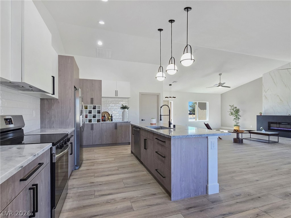 1120 West Gamebird Road Pahrump, NV 89048 - Photo 27 of 36 Kitchen featuring stainless steel appliances, brown cabinets, decorative backsplash, light stone counters, and recessed lighting