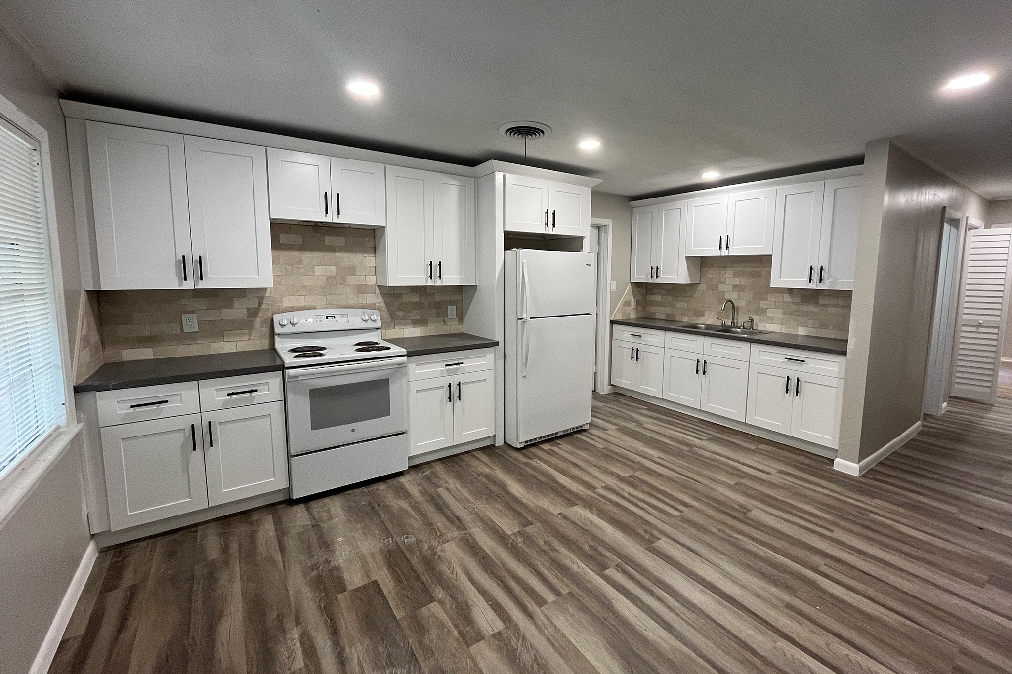 1409 20th Street Huntsville, TX 77340 - Photo 2 of 9 a kitchen with granite countertop white cabinets and white appliances